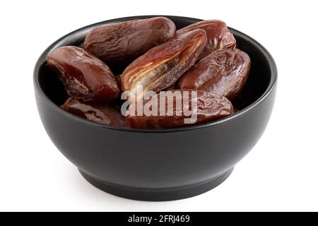 Dry pitted dates and one half date in a black bowl isolated on white. Stock Photo