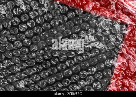 Abstract black red plastic background with bubble wrap and adhesive tape. Diagonal view Stock Photo