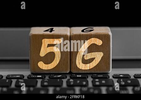 photo on 5G network theme. wooden cubes with the acronym "5G", on the background of laptop Stock Photo