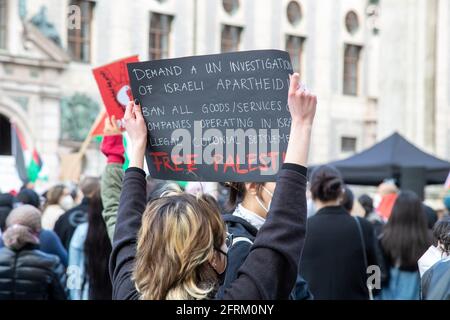 Aktivistin hält Schild mit der Aufschrift: ' Forderung nach einer UN Untersuchung der Apartheid in Israel! Verbot aller Waren und Dienstleistungen aus Israels illegalen Kolonialsiedlungen/Free Palestine '. Ca. 600 Menschen versammelten sich am 20.5.2021 in München, um ihre Solidarität mit den Menschen in Gaza, Ost Jerusalem, den besetzten Gebieten und dem Westjordanland zu zeigen. - Activists holds sign reading: ' Demand a UN Investigation of Israeli Apartheid! Ban all goods/services of companies operating in Israel'S illegal colonial sttlements/Free Palestine '. Around 600 people gather Stock Photo