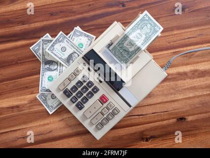 Old fashioned calculator and dollars on a desk Stock Photo