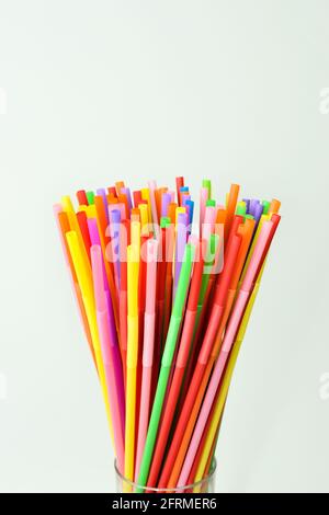 Multicolored cocktail straws in a glass on a white background. Colorful accessory and decoration for a cocktail and drinks party. Stock Photo