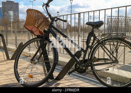 Bike with a grocery basket is parked in an equipped bicycle parking. Riding and cycling in the city. Shopping for groceries and home delivery by bike. Stock Photo