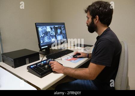 Young man scientist working with scanning electron microscope. Laboratory technician observing samples with a SEM. Stock Photo