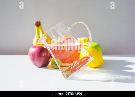 Jug with pure water standing on edge and fruits. Balance concept. Stock Photo