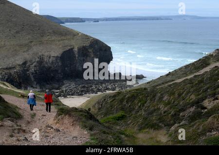 Walkers on the cliffs above a secluded beach in Cornwall . Looking south to St Ives from Chapel Porth Stock Photo