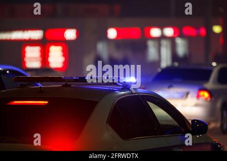 blue police car light at night in city with selective focus and bokeh on black background. Stock Photo