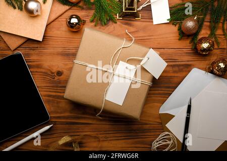 Top view of gift box, tablet, greeting card and decorations in Christmas concept on rustic table Stock Photo