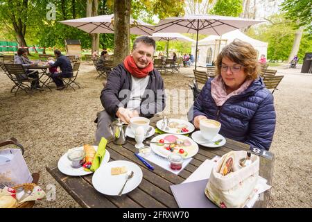 21 May 2021, Hessen, Bad Nauheim: Matthias Görtz and his wife Monika Görtz sit on the garden terrace of the "Schweizer Milchhäusch" at the Bad Nauheim spa gardens in front of a richly laid breakfast table. Thanks to low infection figures, shops, restaurants and cafés in the Wetterau are once again allowed to serve customers and guests. Photo: Frank Rumpenhorst/dpa Stock Photo