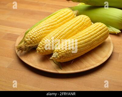 Close up view of corns and corn on the cop on wooden tray on wooden table with copy space Stock Photo