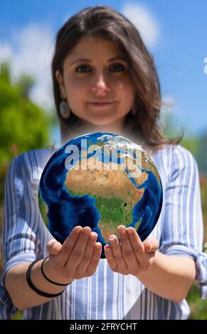 Pretty young woman holding globe on her hands. Environment conservation and energy saving. Ecology and save the planet concept Stock Photo