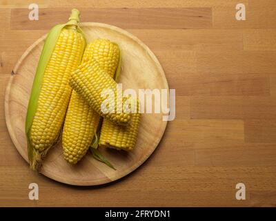 Top view of corns and corn on the cop on wooden tray on wooden table with copy space Stock Photo