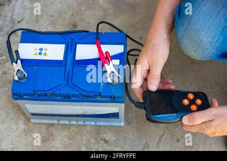 Testing the charging of VARTA car batteries with an electronic multimeter. Stock Photo