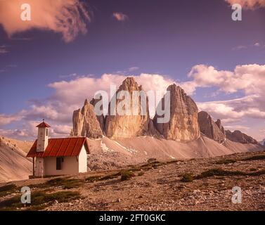 Italy. The image is of the climber chapel at the Drei Zinnen Hut [Rifugio Locatelli] looking towards the famous Three Towers, known in German as Drei Zinnen but more poetically named in Italian as the Tre Cime di Laverado located in the Sexten-Sesto eastern region of the Italian Dolomites. During the First World War, known as the White War the peaks provided a natural barrier between the  Italians and the warring Austrians, the front line running through the peaks. Stock Photo