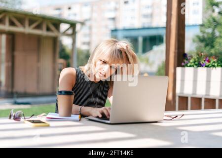 Serious thinking woman working at laptop outside Stock Photo