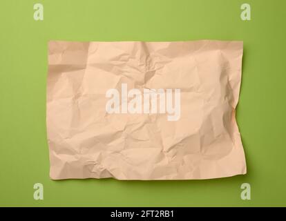 blank crumpled beige sheet of paper on a green background, copy space. A4 format Stock Photo