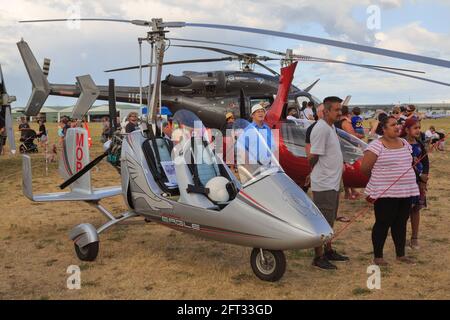 A gyrocopter, a type of light rotorcraft, with a full sized helicopter (a Bell 427) in the background. Photographed at an airshow Stock Photo