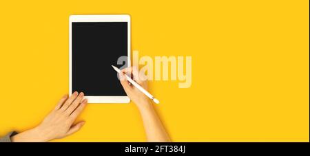 Woman using tablet mockup, hand with stylus pencil, colorful office workspace with yellow background, cop space, education concept banner photo Stock Photo