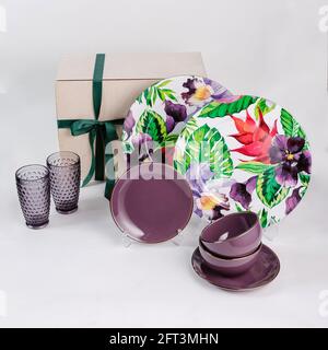 Closeup of a gift set with bowls, drinking glasses, flowery plates isolated on a white background Stock Photo