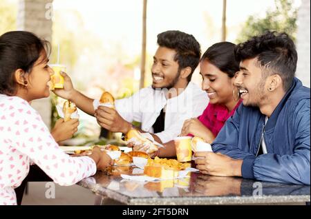 Focus on front Boy, Group of friends having fun and laughing while together eating breakfast at restaurant table - Teenager Students having fun Stock Photo