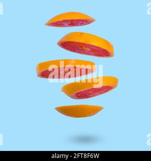 Floating levitating ripe grapefruit on a light blue background. Vitamins, healthy diet concept. Minimal fruit idea. Sliced grapefruit floating in the Stock Photo