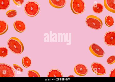 Frame of sliced fresh grapefruit isolated on light pink background. Vitamins, healthy diet and detox concept. Sliced grapefruit floating in the air. M Stock Photo