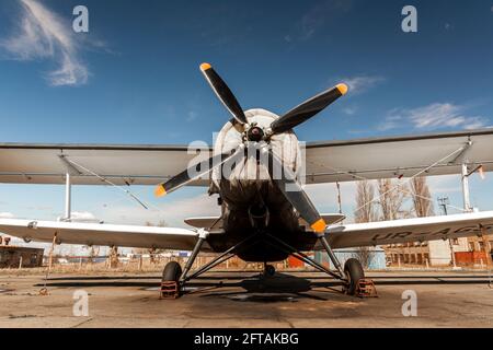 Light single-engine airplane - front view: propeller with four blades, wing and wheels. the engine of this historical biplane is covered with a cover. Stock Photo