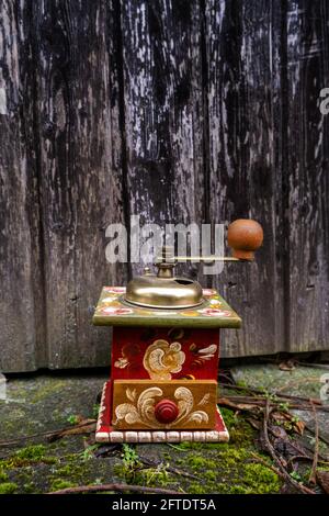 close-up of an old painted coffee grinder outsdie in front of weathered wooden door Stock Photo