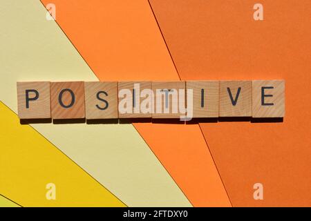 Positive, word in wood alphabet letters isolated on colourful background Stock Photo