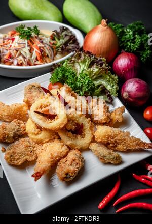 A Dish of Deep Fried Battered Seafood Tempura Sided with Thai Spicy Mango Salad Stock Photo