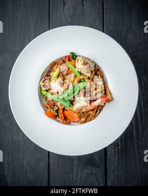 A Dish of Thai Pad See Ew Noodle with Seafood and Vegetables on Black Wooden Background Stock Photo