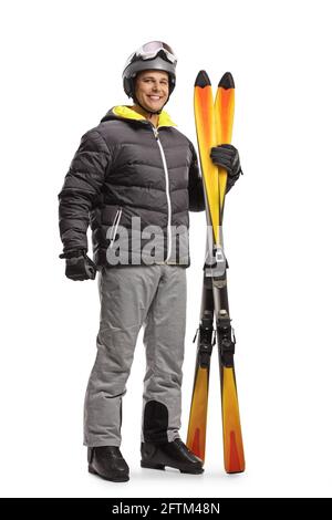 Full length portrait of a young man holding a pair of skis isolated on white background Stock Photo
