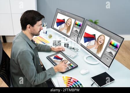 Designer And Photographer Using Multiple Computer Screens Stock Photo