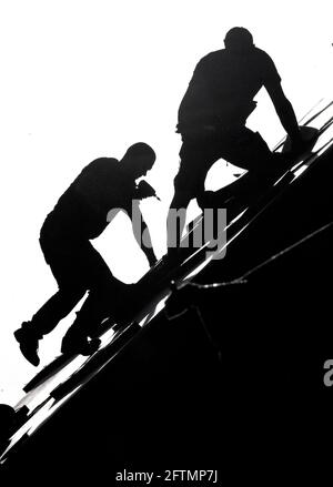 Silhouettes of two roofers working on the roof of a house.  Photo Janerik Henriksson / TT code 10010 Stock Photo