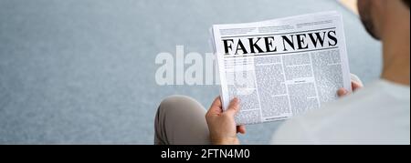 Businessman Reading Fake News Article On Newspaper In Living Room Stock Photo