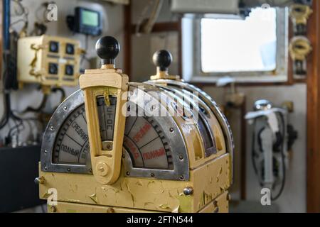 Navigational bridge on abandoned vessel. Old derelict ship wheelhouse. Ship's control device. Russian words: Ahead/Astern, full, half, slow, dead slow Stock Photo