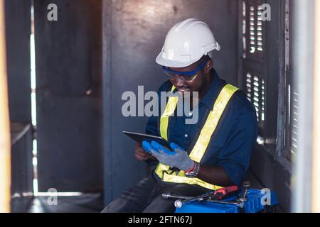 Industry engine technicians are using the tablet to research engine system within the control room Stock Photo