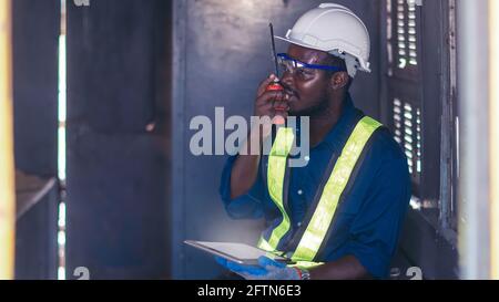 Industry engine technicians are talking with walkie talkie and using the tablet to research engine system within the control room Stock Photo