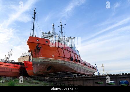 Tug vessel ashore on ship repairing yard. Summer time. Stock Photo