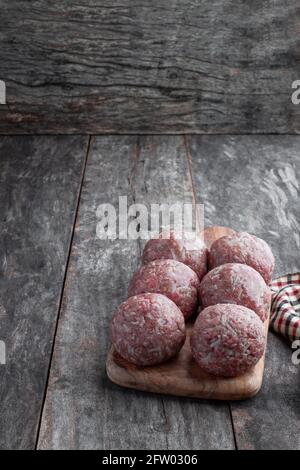 Raw meat  balls on wooden cutting board on rustic table Stock Photo