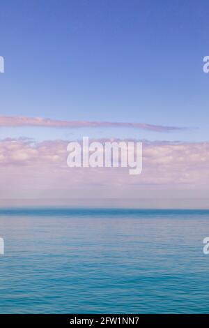 the calm scene of sunrise, of pink cotton candy clouds over the marine blue ocean Stock Photo