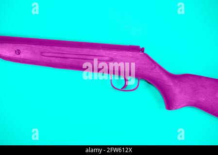 Old vintage pink air rifle on trendy turquoise background. Minimal abstract weapon concept. Stock Photo