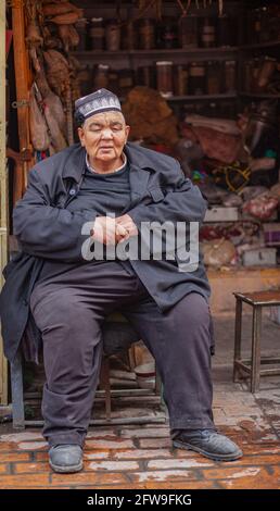 Large man sitting outside his tent Kashgar, Xinkiang, Popular Republic of China, 2019 Stock Photo