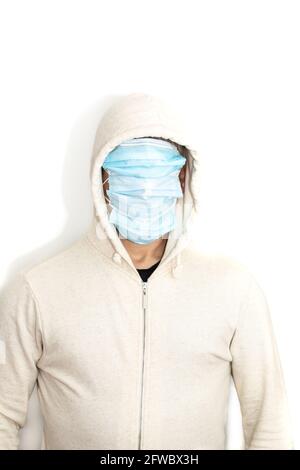 Vertical portrait of hooded man with his face covered in protective masks with white jacket and white background Stock Photo
