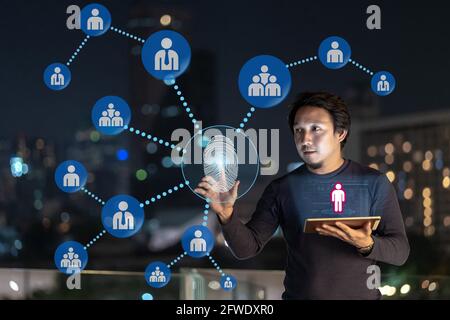 Asian creative freelancer using technology tablet with authentificate by fingerprint and AR for connected with people icon over the financial district Stock Photo
