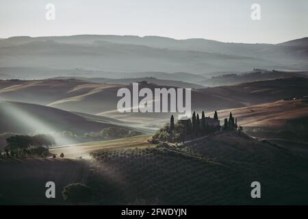 Podere Belvedere Villa in Val d'Orcia Region in Tuscany, Italy at Sunrise or Dawn in a Mysterious Morning Mood near San Quirico Stock Photo