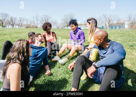 Group of runners in a park lying on the grass. Talking and laughing. Stock Photo
