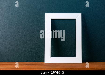 Minimal interior composition with black wall and white blank photo frame on the wooden table, decor mockup, space for text Stock Photo