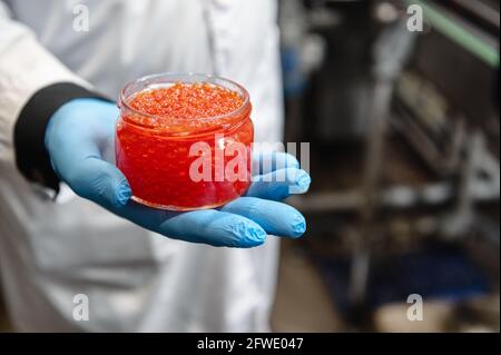 Glass jar of red caviar in the palm of your hand. Jar without a lid. Stock Photo