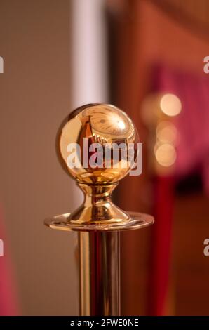 Fragment of a gold candelabrum on a blurred background of red theater chairs. Vertical. Stock Photo